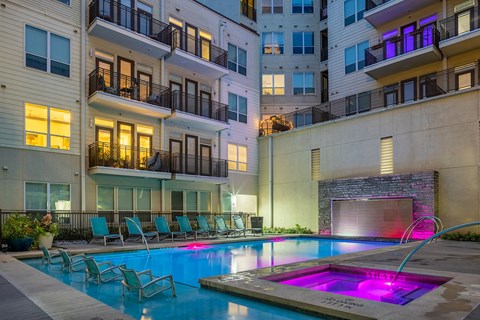 a swimming pool with chairs in front of an apartment building
